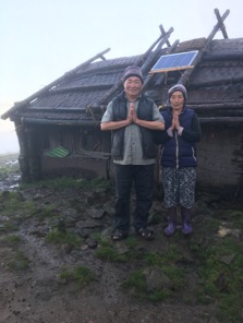 A Tibetan nomad couple outside their home with their new solar panel which provides lighting indoors