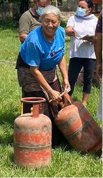 Lady in Paljor Ling settlement collecting her refill gas cylinder and returning her empty one